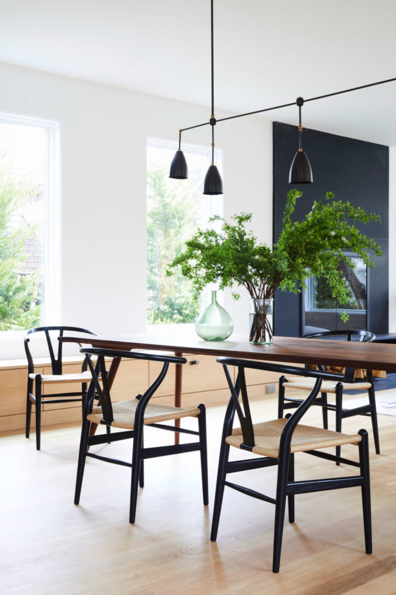 The dining space is done with a dining table and some eye-catchy bone chairs, black and brass lamps over the table mark the table