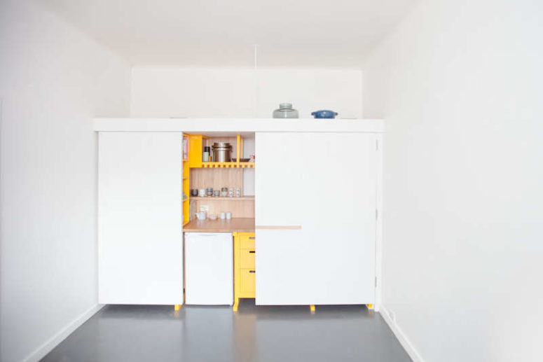 The kitchen design is done with light-colored wood to contrast thesunny yellow cabinets