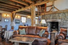 03 The living room features a selection of rustic and vintage furniture and a large fireplace with firewood storage