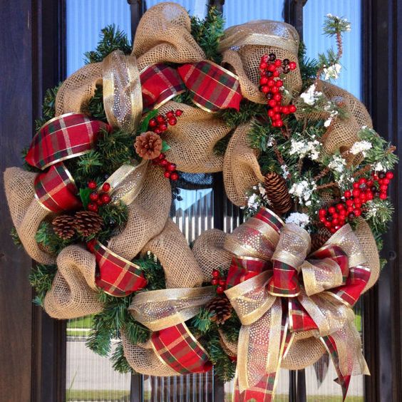 a burlap wreath with plaid and gold ribbon, pinecones, berries and evergreens for a Christmas door