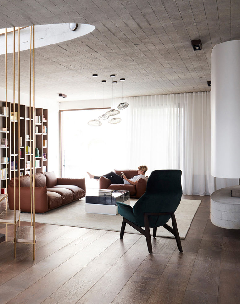 cool suspended fireplace The living room is done with a suspended fireplace, leather upholstered furniture and a large bookcase wall that hides the study