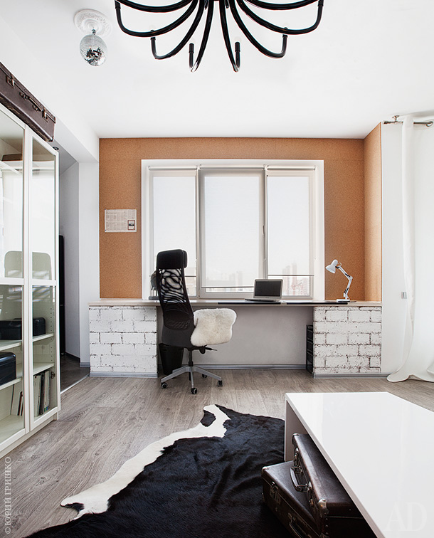 The working space is done with an orange wall, brick pillars, and it's filled with natural light