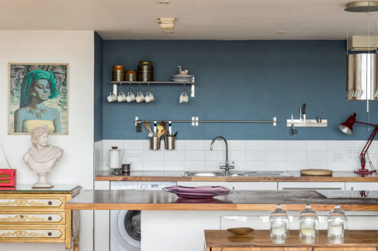The kitchen features white cabinets with wooden countertops, a graphite grey wall and a white tile backsplash