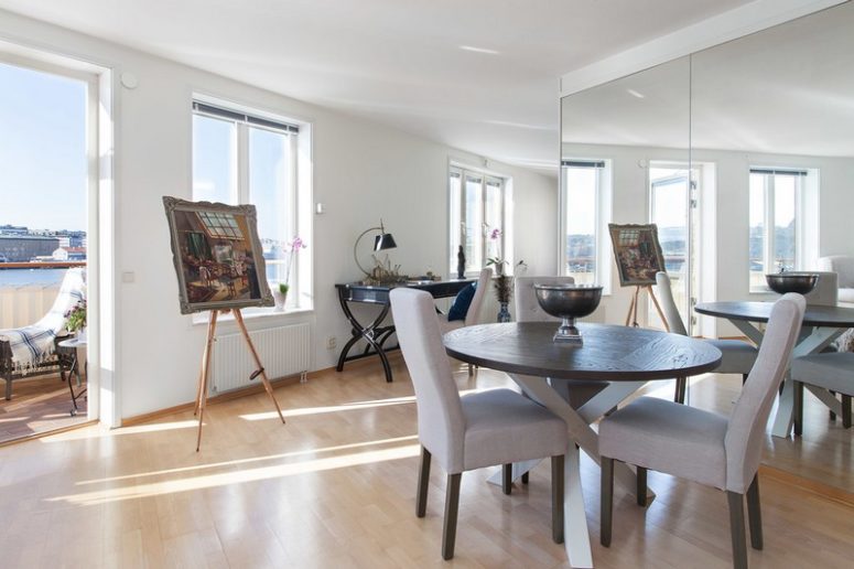 There's a large mirror that accentuates the river views and a dining zone with a round wooden table