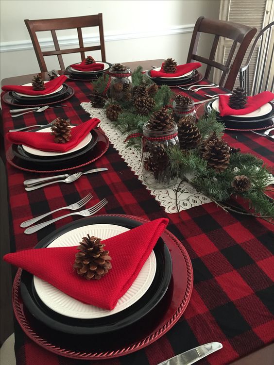 a plaid tablecloth, red napkins and lots of pinecones and evergreens for a rustic tablescape