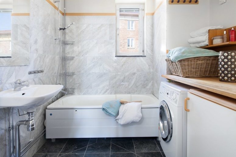 The bathroom is clad with grey marble tiles and black marble ones, there's everything necessary