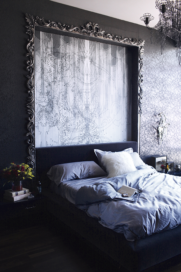 The master bedroom id one with a velvet upholstered bed and a giant headboard with an artwork and a vintage frame