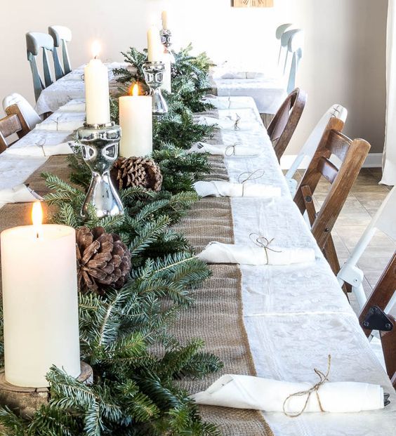 a burlap table runner, an evergreen garland, candles and large pinecones for a cozy rustic feel