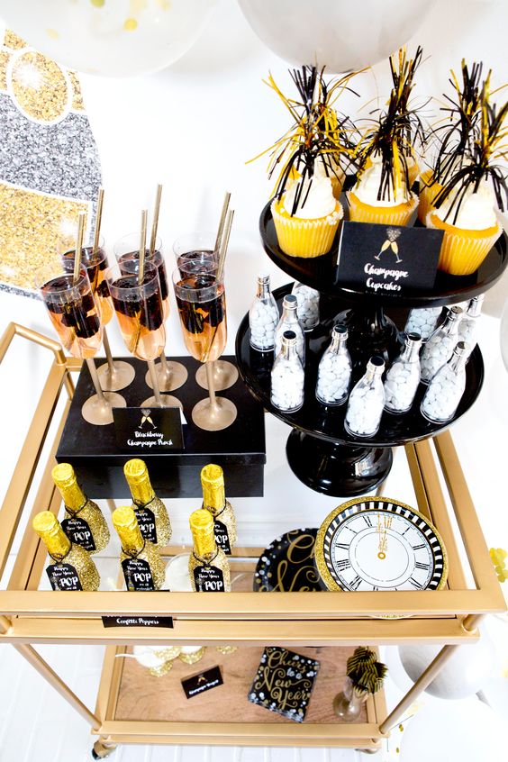 a brass bar cart with glitter bottles, fringe cupcake toppers and a glitter clock