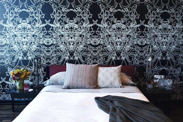 The second bedroom is done with black and white graphic wallpaper and a purple upholstered bed for a contrast