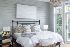 09 a rustic bedroom with a gla feel and a large basket at the foot of the bed for storing pillows