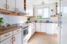 10 The kitchen features white cabinets and natural wood touches that make the space comfier