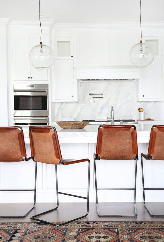 chic amber leather stools add color to a monochromatic kitchen and make it more interesting