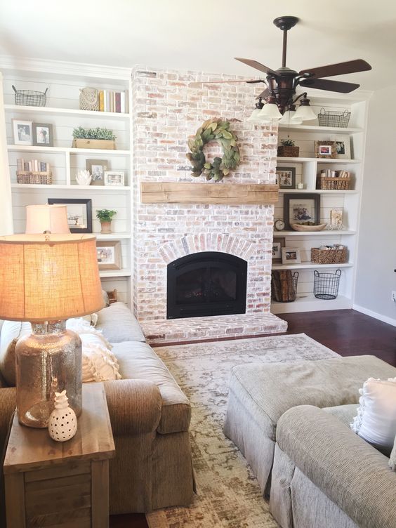 a whitewashed red brick fireplace with a wooden mantel for a neutral rustic space