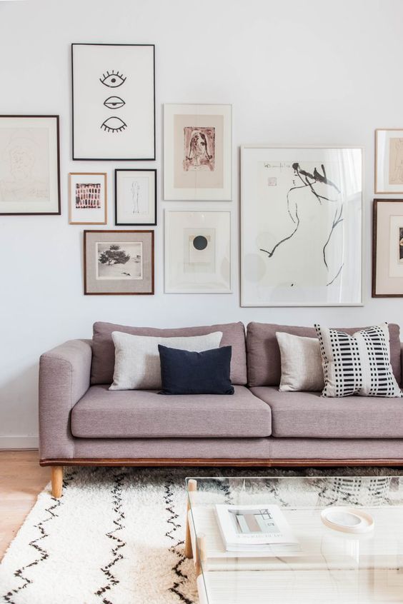 a modern living room with a whole gallery wall over the dusty pink sofa