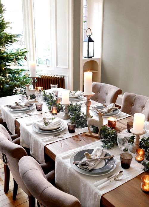 a chic neutral tablescape with candles, evergreens, deer figurines, faux birds and branches