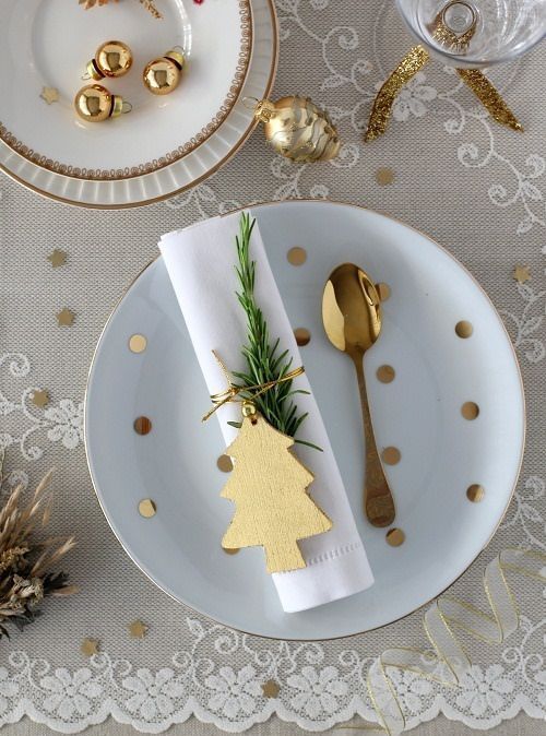 a lace tablecloth, gold ornaments, a wooden tree napkin tag and evergreens for a cute tablescape