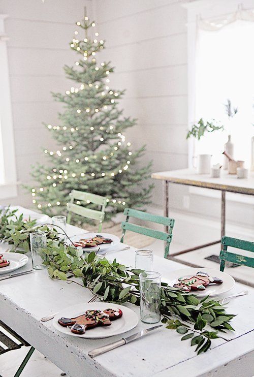 a modern table setting with a foliage garland and large gingerbread men cookies for a cool look