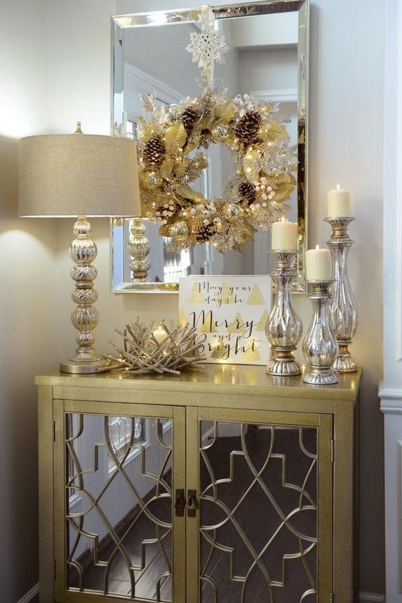 a gold wreath with beads and pinecones, mercury glass candle holders and a nest-style candle holder for a glam feel
