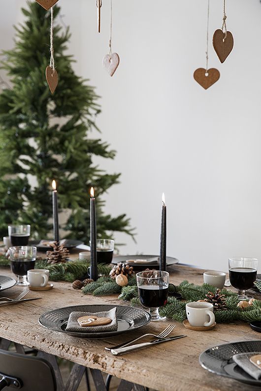 an evergreen garland with pinecones and nuts, black candles and gingerbread cookies hanging from above