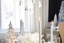 22 a white and silver table setting with pearly and silver ornaments, a crystal chandelier and patterned glasses