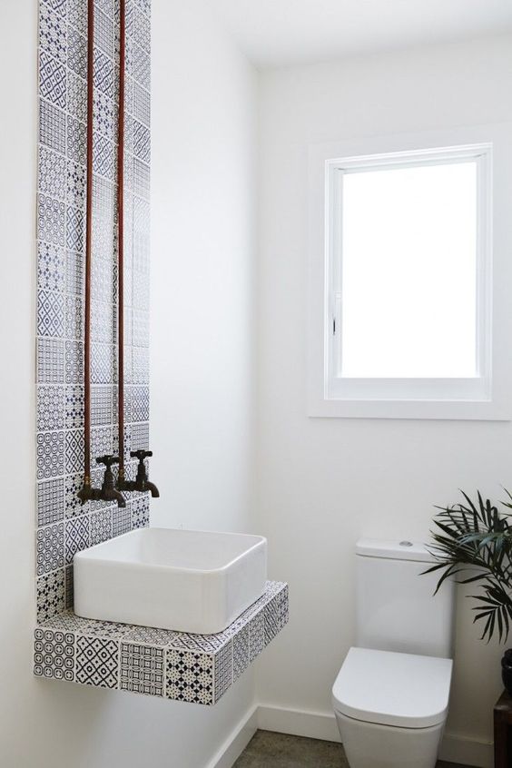 a tiny powder room in white distracts attention from its small size with graphic black and white tiles