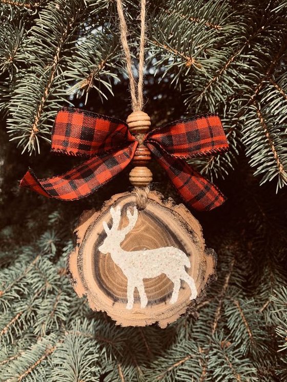 a beautiful rustic Christmas ornament made of a wood slice with a live edge, wooden beads and a plaid bow