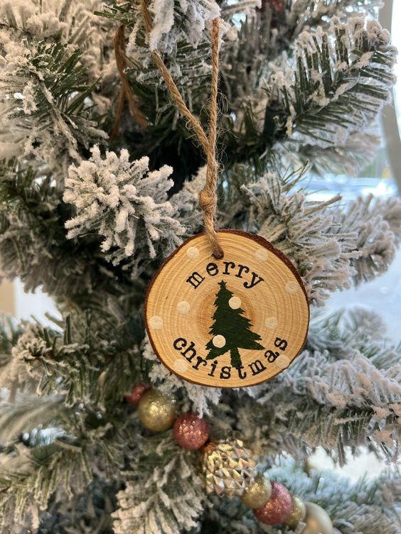 a rustic Christmas ornament of a tree slice with a black tree and snow is a lovely idea that can be easily realized