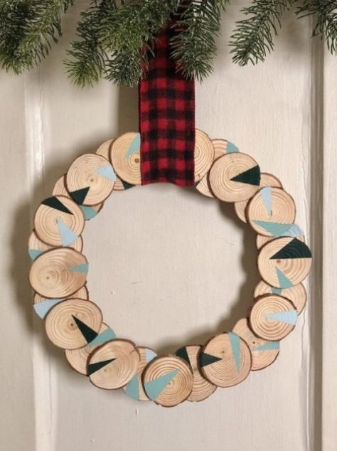 a wood slice Christmas wreath with geometric design and a plaid ribbon is a cool bold decoration idea