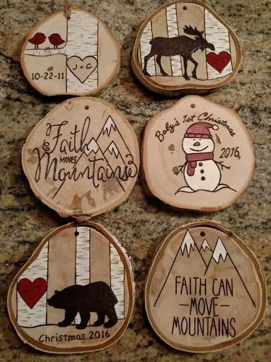 wood burnt and painted wood slice ornaments with snowmen, a moose, a bear and mountains