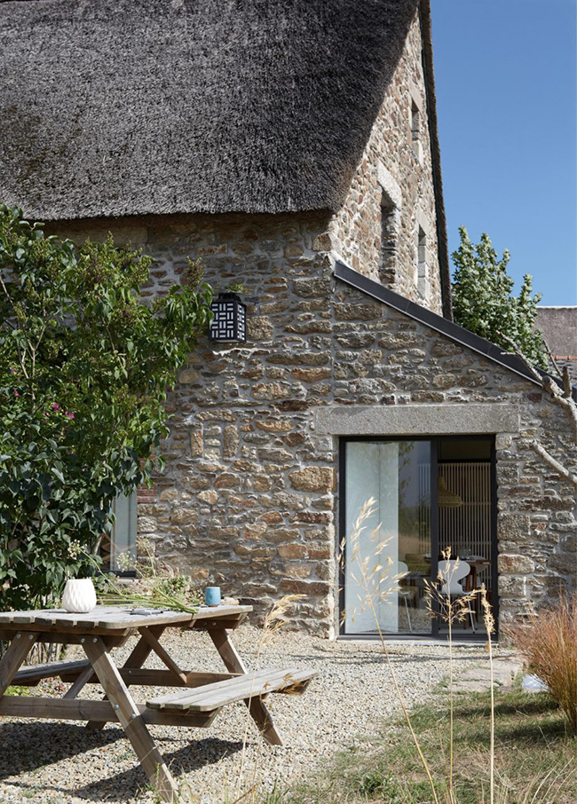The exterior is left as it is, with stone clad and a rustic outdoor dining set