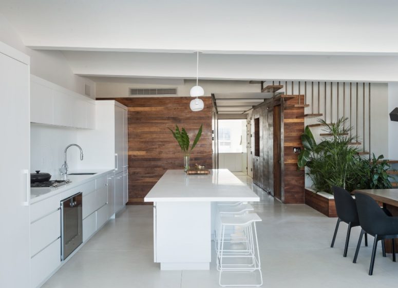 white kitchen design The kitchen is done with white cabinets and a white kitchen island, the wood clad walls create a contrast