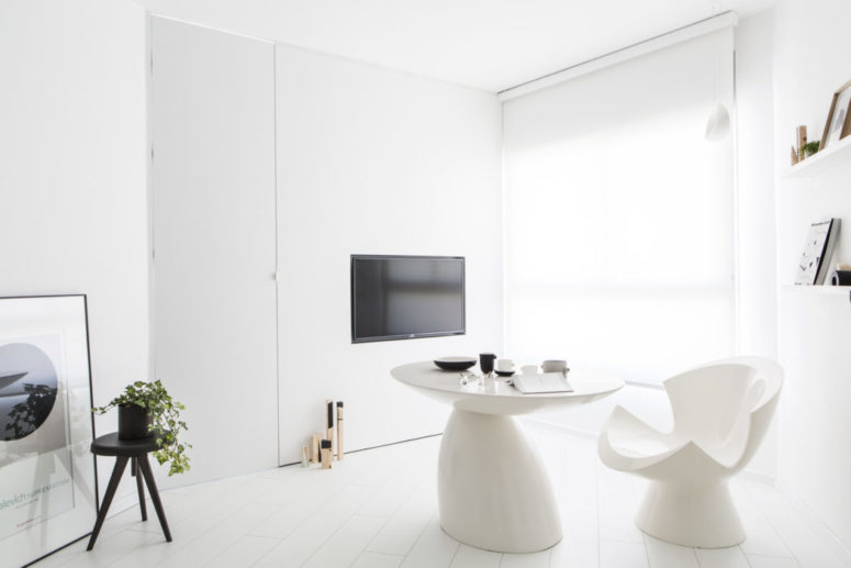 The living room doubles as a dining space, it has a comfy table and some eye-catchy chairs, a TV and bookshelves