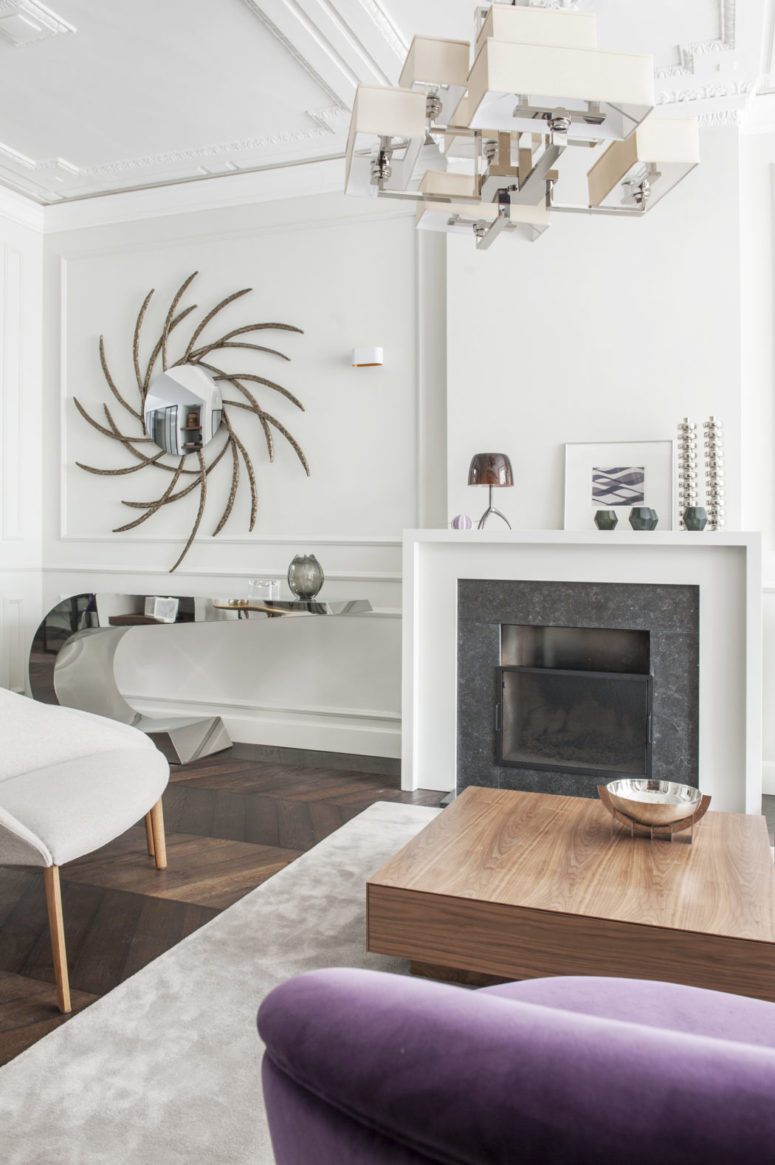 The living room shows off a unique geometric chandelier, a sculptural mirrored console and a fantastic mirror