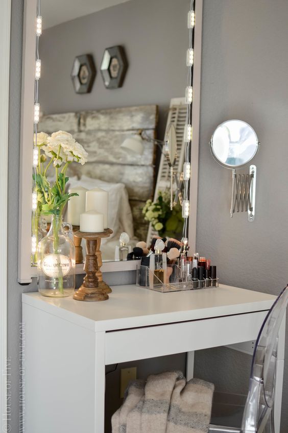 a chic makeup space with a Micke desk, an acrylic chair, a lit up mirror and a comfy makeup unit