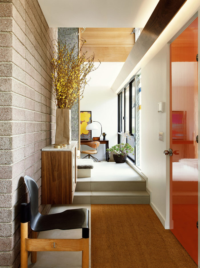 cute workspace in the middle of the home In the end of this corridor you may see a workspace done with a bold artwork, mid-century modenr furniture and a glazed wall that brigns much light inside