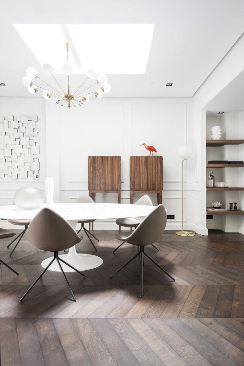 The dining space features a geo artwork, some wooden cabinets, built-in shelves and a modern dining zone with egg-like chairs