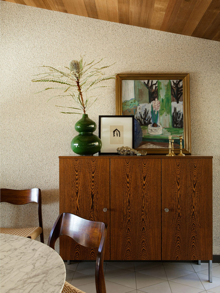 The dining space is done with cool mid-century modern chairs, a cabinet and a marble top table, the art fits the space perfectly