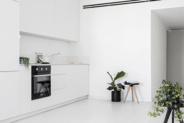 The kitchen is done with sleek white cabinets and lots of potted greenery enliven the minimalist space The kitchen is done with sleek white cabinets and lots of potted greenery enliven the minimalist space