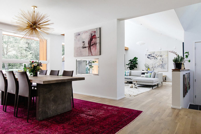 The living room is partly divided from the dining room with a fuchsia rug, a bunburst chandelier and a bold artwork The living room is partly divided from the dining room with a fuchsia rug, a bunburst chandelier and a bold artwork