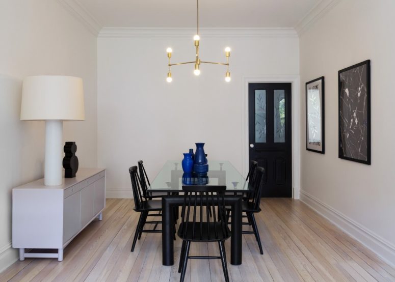 The dining space is done with an eye catchy black dining set with a cool glass tabletop, a sideboard and a stylish brass chandelier The dining space is done with an eye-catchy black dining set with a cool glass tabletop, a sideboard and a stylish brass chandelier