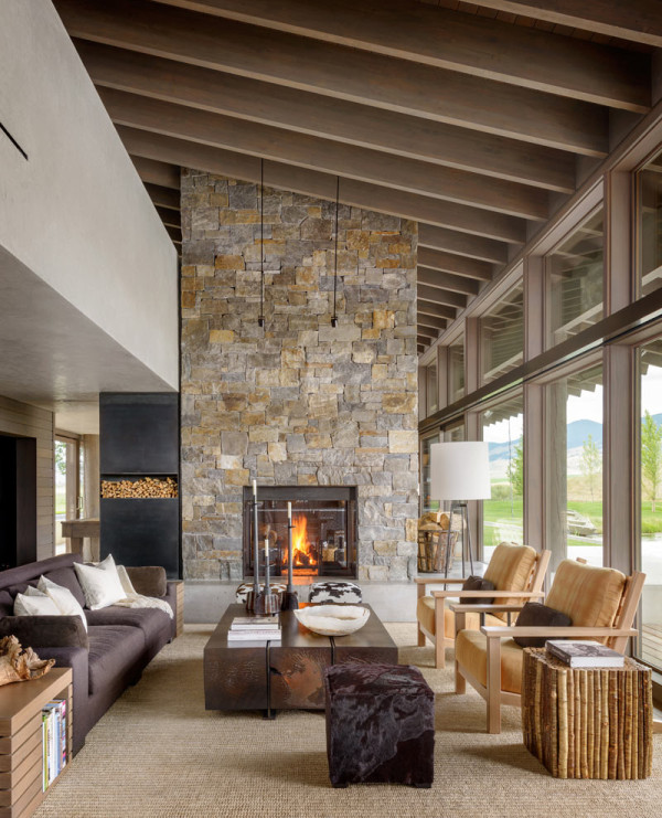 classic stone clad fireplace The living room features a large stone clad fireplace, some wooden furniture, faux fur and velvet that are used for a cozy feel