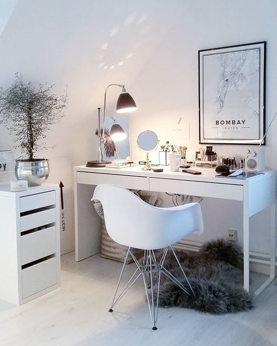 a chic makeup nook done in Scandinavian style, with a lamp and several mirrors, makeup stored in a drawer unit