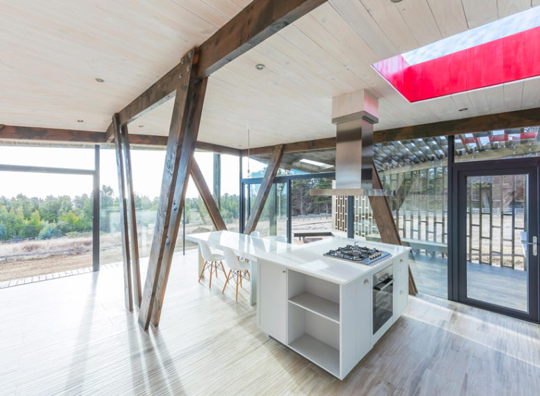 kitchen with wooden beams The kitchen is done with minimalist white furniture and wooden beams that echo with the wooden shell outside