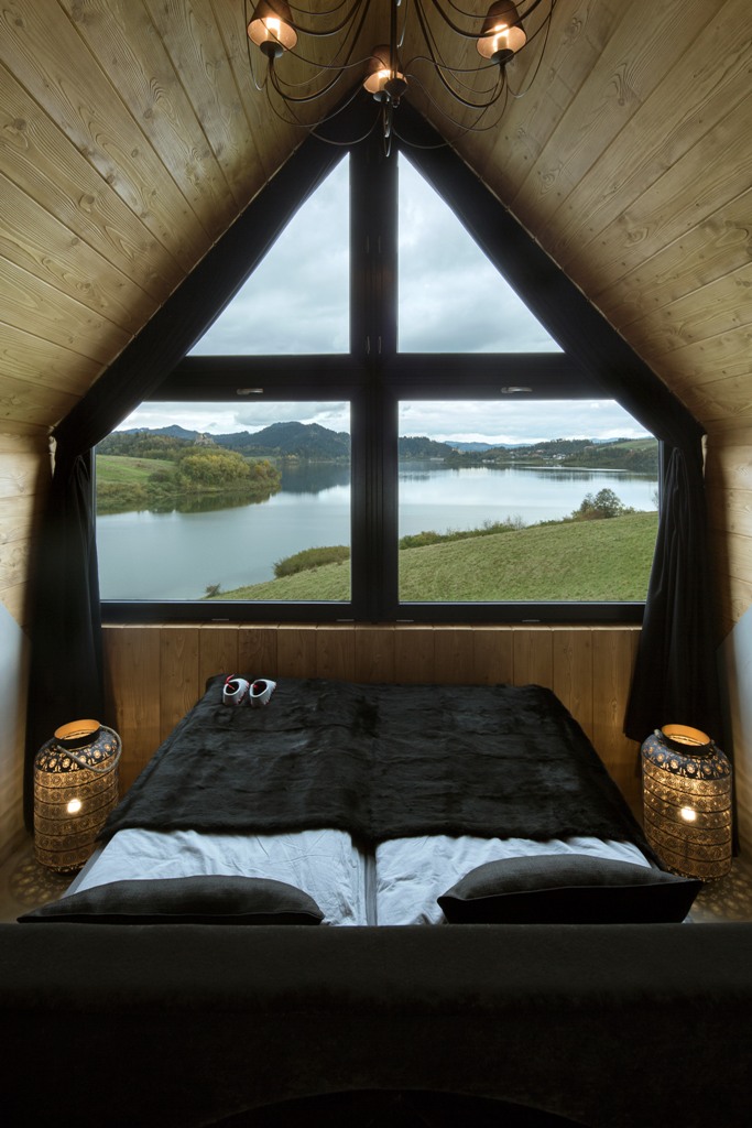 The master bedroom is centered around the views, there's an upholstered bed with some drawers and lanterns