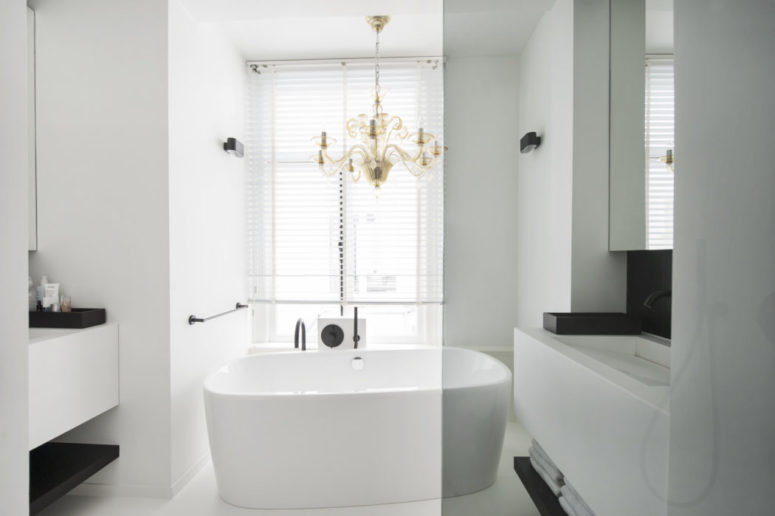 brass detail for a modern bathroom The master bathroom is done in white, with black accents and a brass chandelier over the bathtub