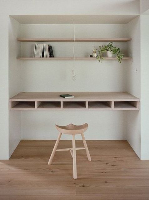 a built-in workspace with floating shelves and a comfy desk with storage inside