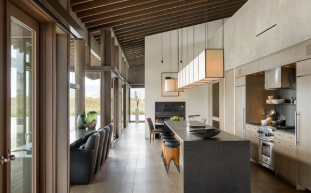 The kitchen is done with beige cabinets, a stone clad kitchen islands and a dining space along the window to enjoy the views