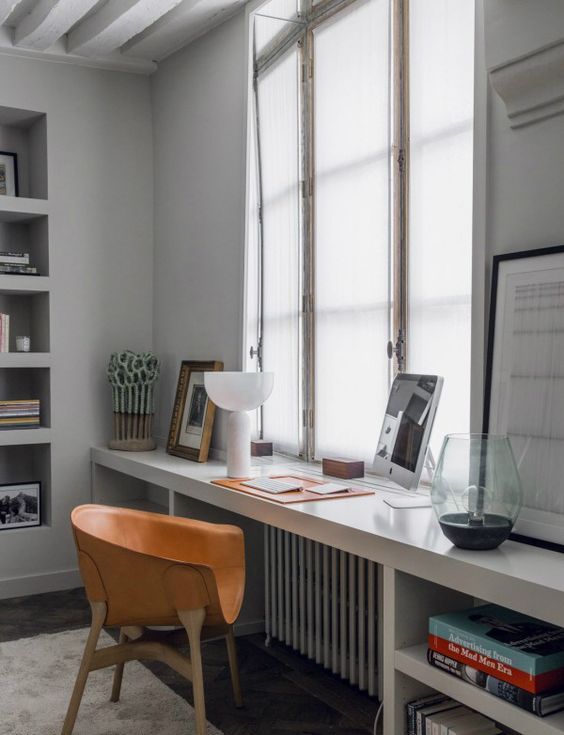 a modern windowsill desk with open storage shelves on both sides and a comfy leather chair