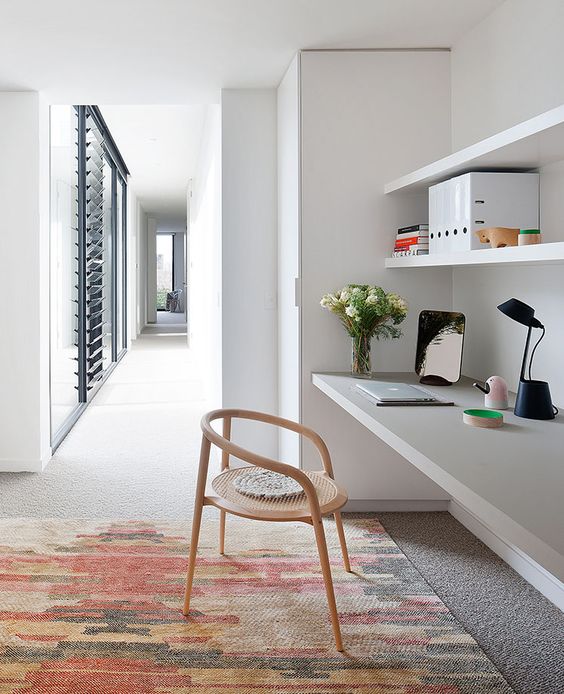 a comfy modern home office with floating shelves and a matching desk below plus a fun chair